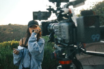 A crew member on the radio beside the camera on the hillside