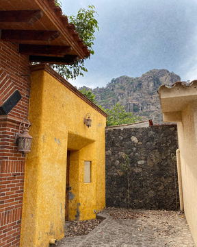 An ochre wall and a stone wall under a rocky ridge